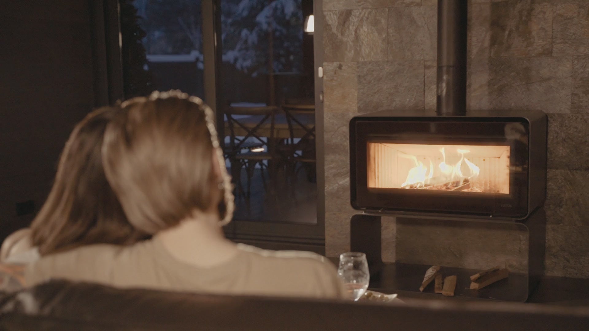 A bearded man sitting on a couch, enjoying a warm fireplace with the love of his life. Confident, connected, and present.